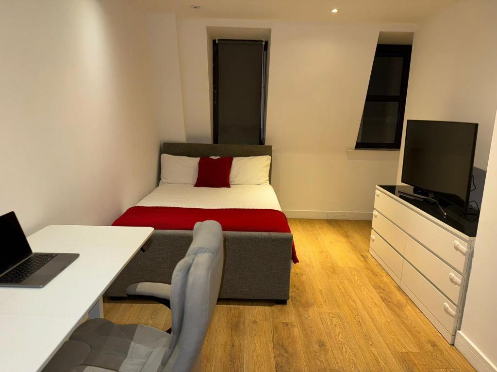 Kleines Zimmer mit einem Bett und einem Schreibtisch mit einem Laptop. in der Unterkunft studio flat in streatham in London