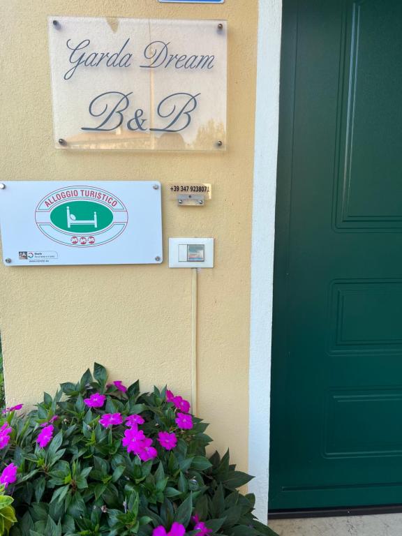 a green door and a sign on a house with flowers at Garda Dream in Lazise