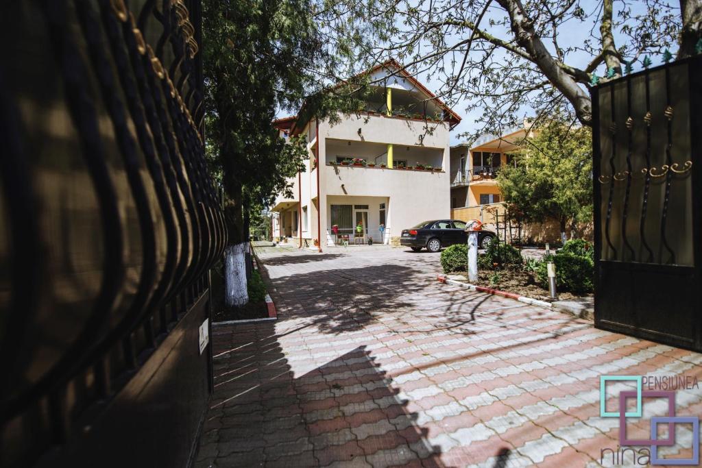 a house with a fence in front of a driveway at Pension Nina in Douăzeci şi Trei August