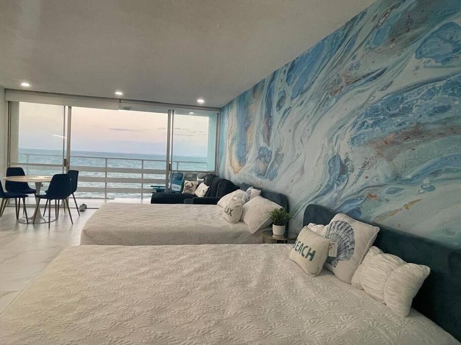 a bedroom with two beds and a large painting on the wall at Beautiful Ocean Blue Love oceanfront apartment in Fajardo