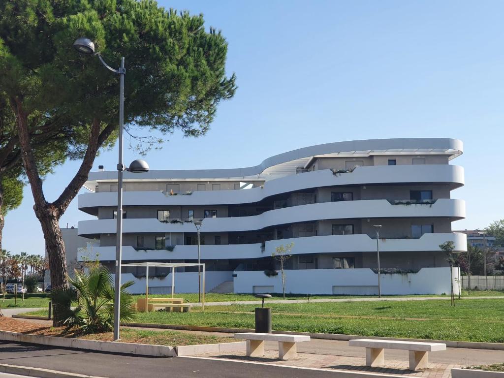 un bâtiment avec un arbre et des bancs devant lui dans l'établissement WATERFRONT, à Montesilvano