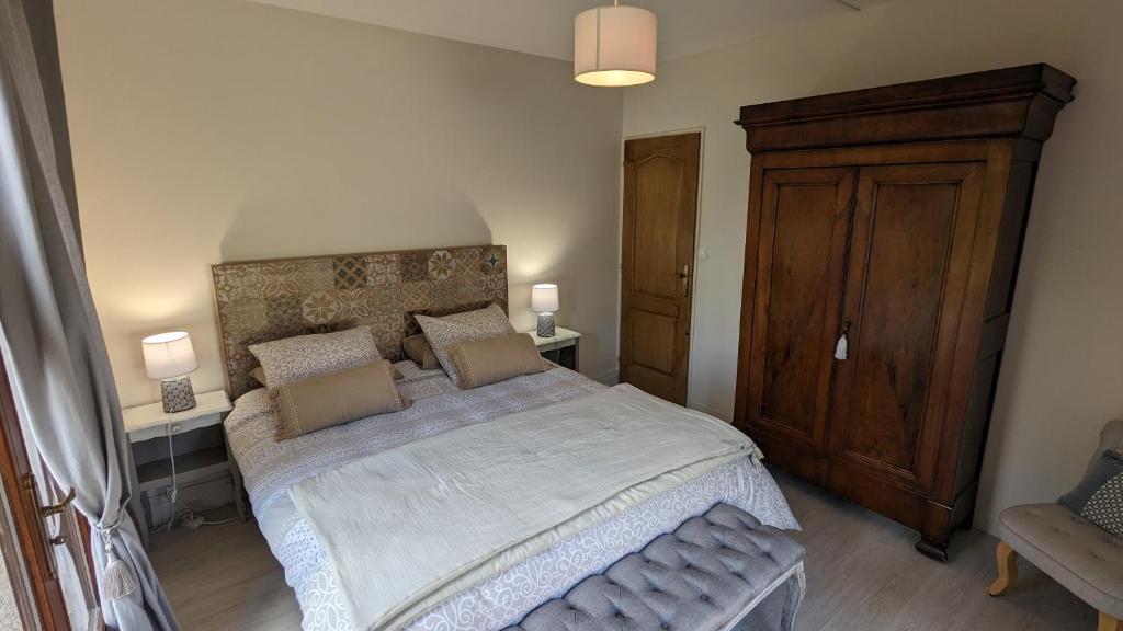 a bedroom with a large bed and a wooden cabinet at Au Bonheur de Cisse in Chouzy-sur-Cisse