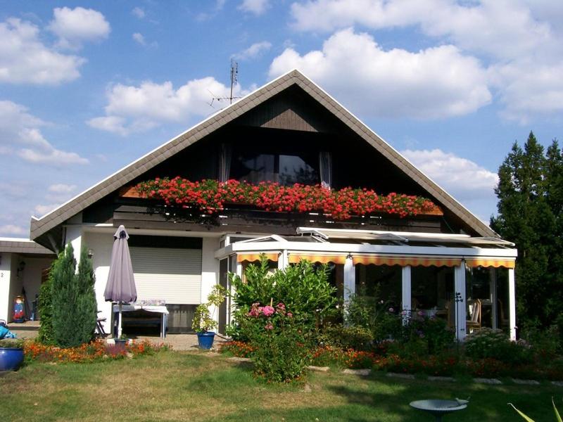 a house with a balcony with flowers on it at Pension C Blickfeld in Winsen
