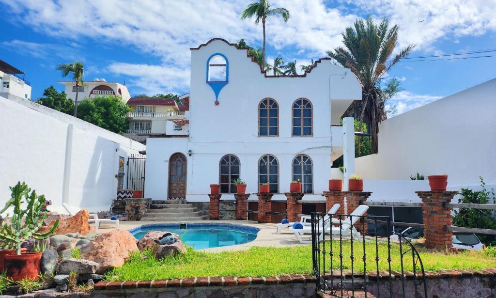 a white house with a swimming pool in front of it at Hill House Mazatlan - Bed & Breakfast in Mazatlán