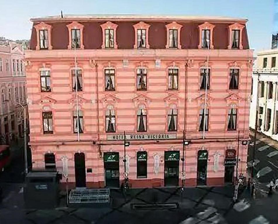 un gran edificio rosa en medio de una ciudad en Hotel Reina Victoria, en Valparaíso