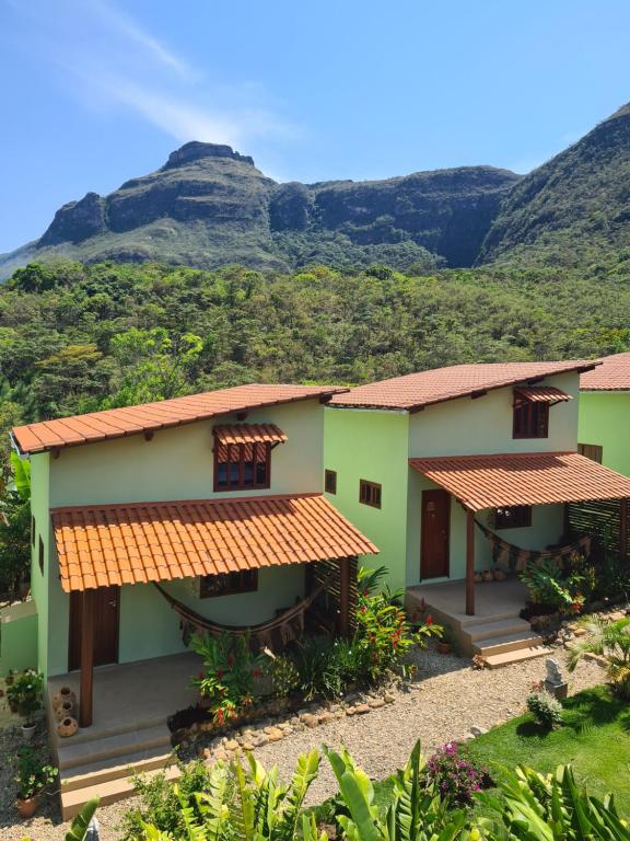 a view of two houses with mountains in the background at Green Chales - Vale do Capão in Vale do Capao