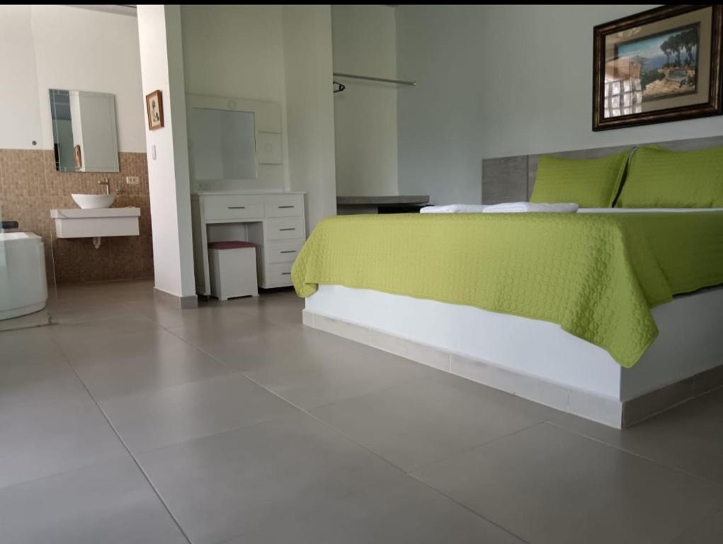 1 Schlafzimmer mit einem grünen Bett und einem Badezimmer in der Unterkunft Hostería Las Palmas in Tena