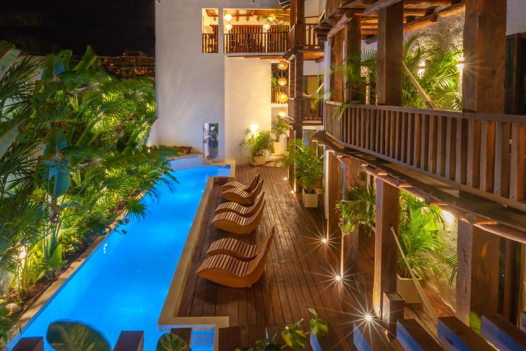einen Blick über einen Hotelpool mit Stühlen und Pflanzen in der Unterkunft Aparthotel Onda Maya - Adults Only in Holbox