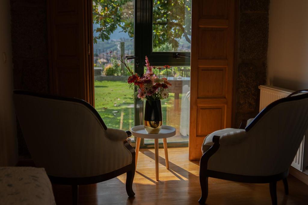 a room with two chairs and a vase with flowers on a table at Casa A Chairiña y A Revolta in Arnoia