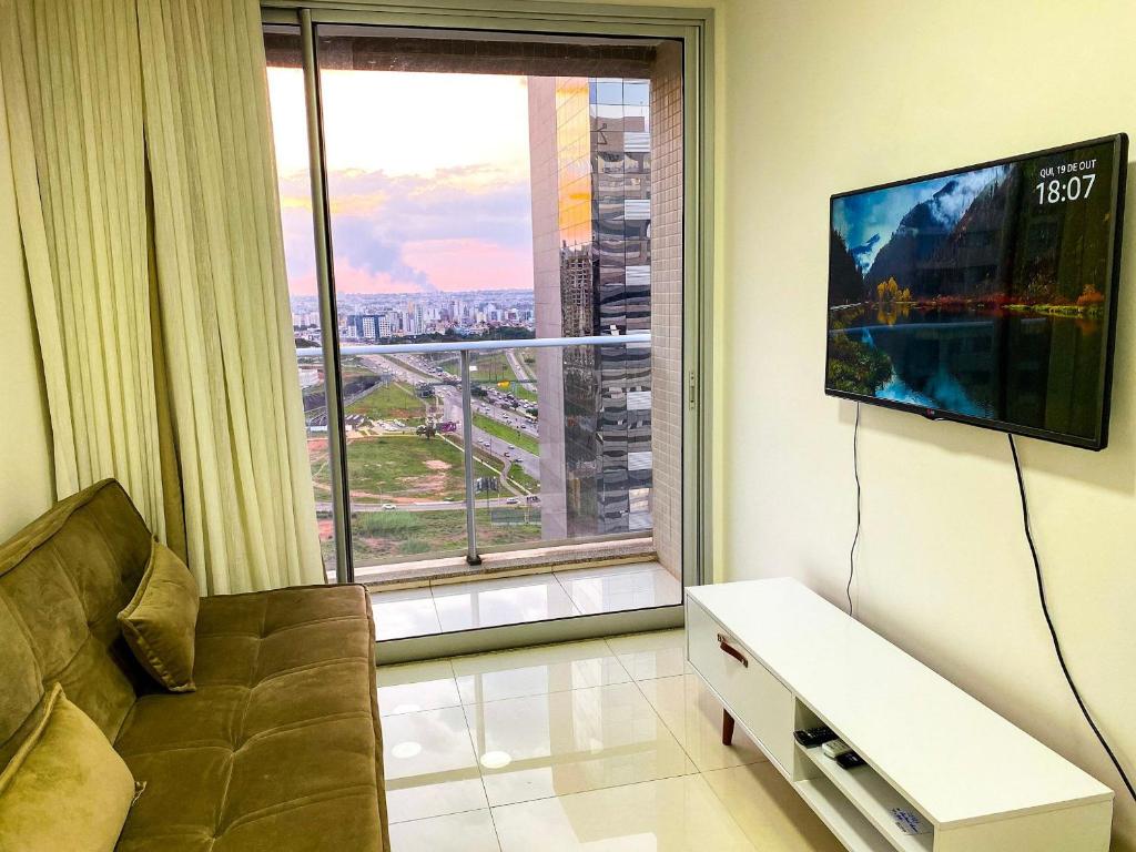 a living room with a couch and a large window at O melhor apartamento no shopping in Águas Claras