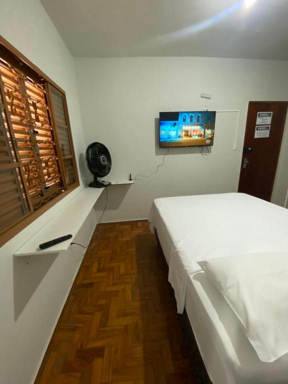 Pousada automática sem recepção 1 في أبرلانديا: غرفة نوم مع سرير وتلفزيون على الحائط