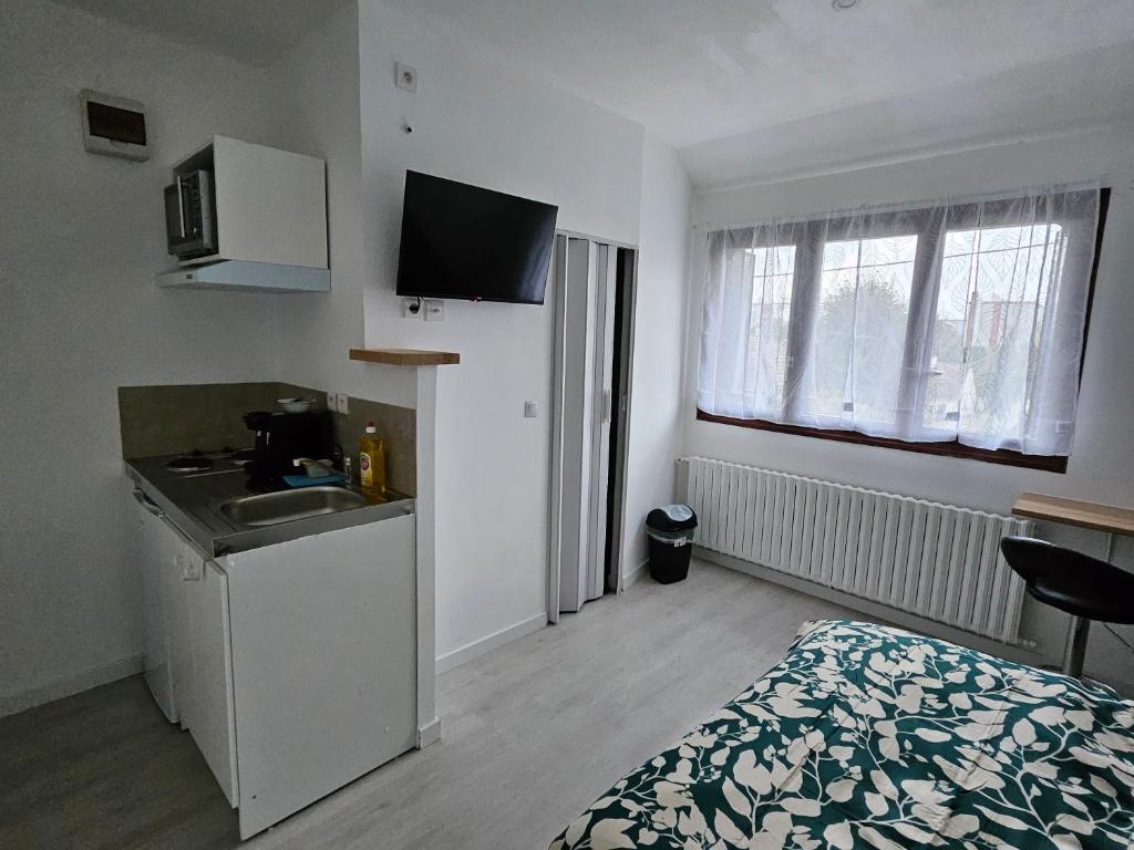 Cette petite chambre dispose d'une cuisine, d'un lit et d'un lavabo. dans l'établissement Joli studio équipé de 16m2, à Neuilly-sur-Marne