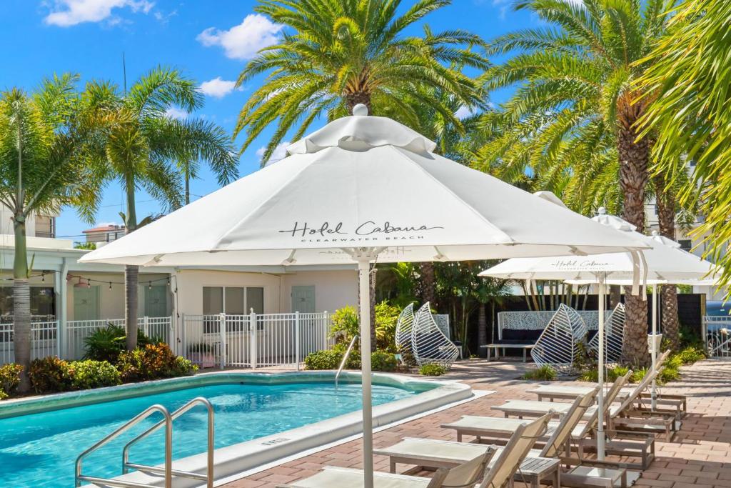 a pool with chairs and an umbrella next to a swimming pool at Hotel Cabana Clearwater Beach in Clearwater Beach