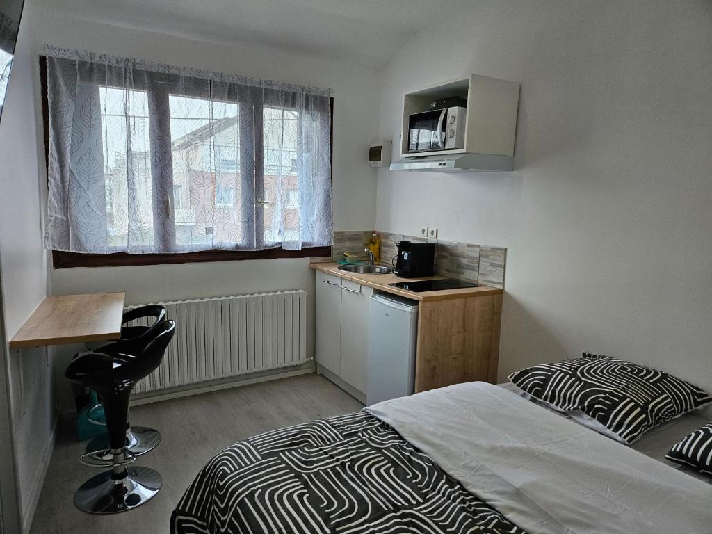 Una pequeña habitación con una cama y una cocina. en Charmant studio équipé de 14m2, en Neuilly-sur-Marne