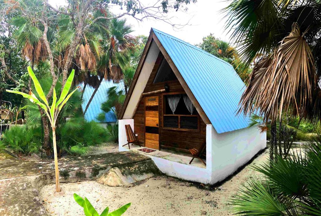 una pequeña casa con techo azul en una playa en Kin Resort Lodge en Maya Beach