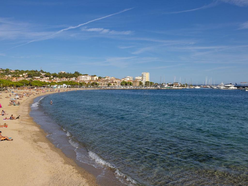 a beach with people laying on the sand and the water at Apartment La Palmeraie II-1 by Interhome in Sainte-Maxime