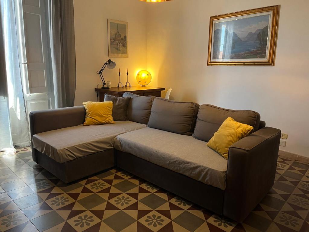 Sofá marrón en la sala de estar con almohadas amarillas en Casa Caruso, en Catania