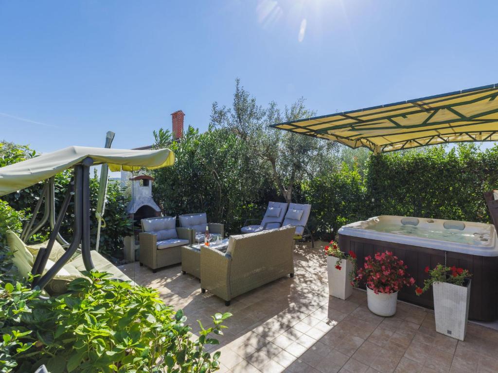 a patio with chairs and a hot tub and an umbrella at Holiday Home Nena by Interhome in Buje