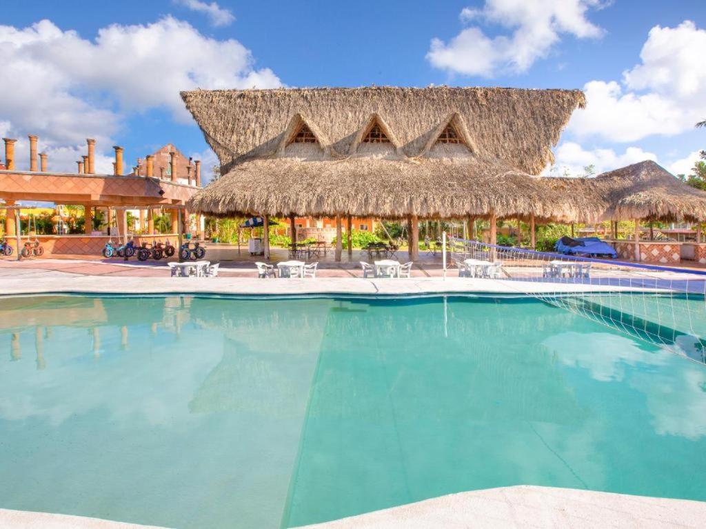 a resort swimming pool with a thatched roof at Hacienda Ixtlan Cozumel in Cozumel