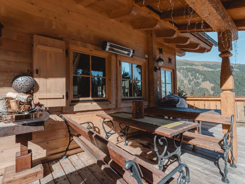 a wooden cabin with benches and a table on a deck at Chalet Königsleiten 3 by Interhome in Königsleiten