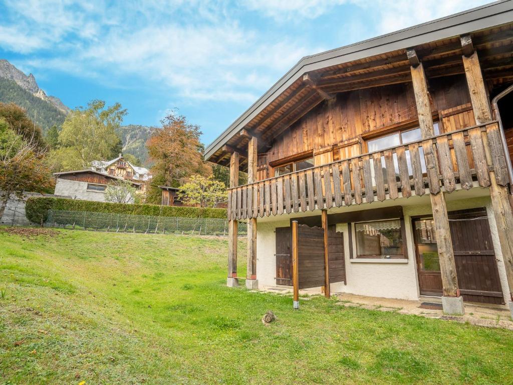 une maison en bois dans un champ avec des montagnes en arrière-plan dans l'établissement Apartment Clos des Outannes-1 by Interhome, à Chamonix-Mont-Blanc