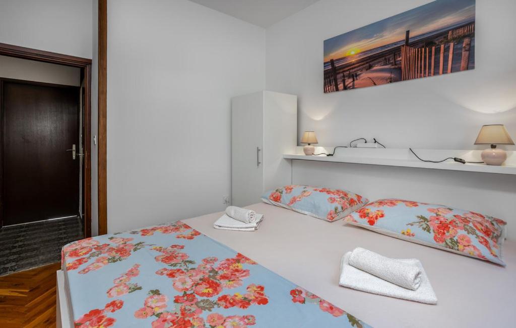 a white bedroom with a bed with floral sheets and pillows at Apartments Drazen in Crikvenica