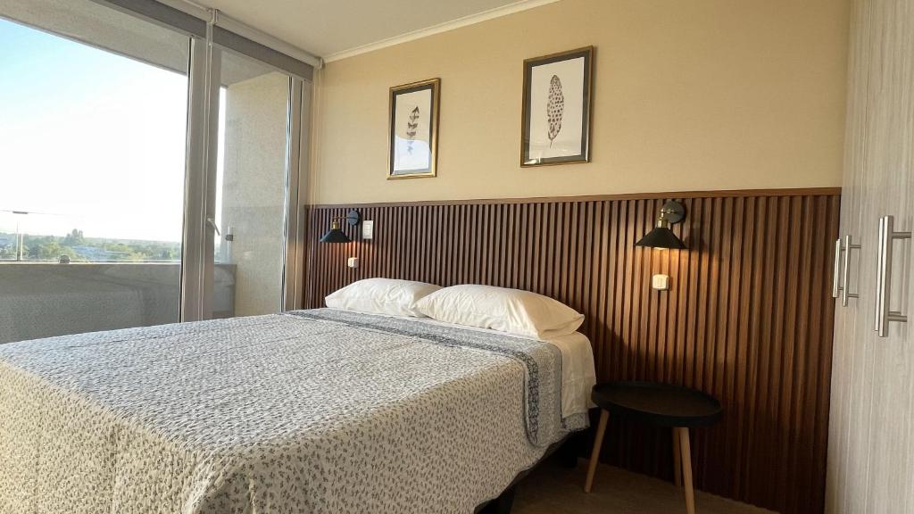 a bedroom with a bed and a window at Depto central, parking, moderno in Chillán
