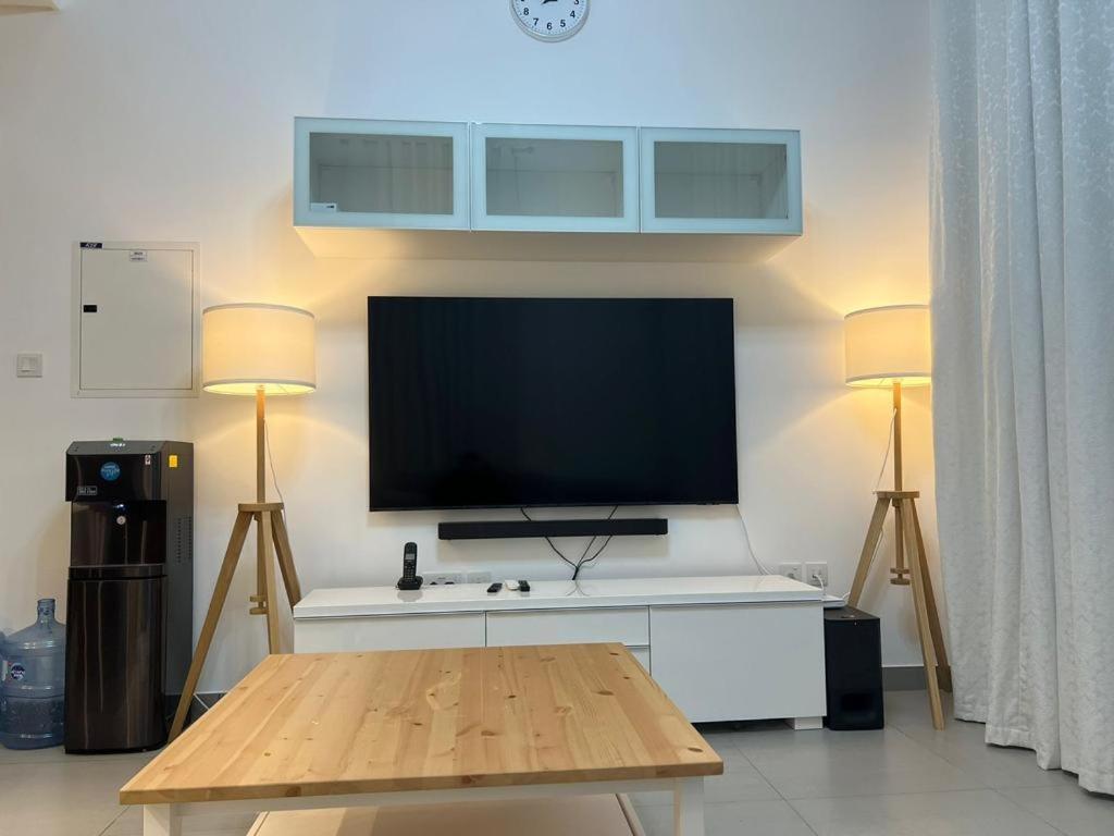 a living room with a tv and two lamps and a table at Sharjah Brand New Apartment in Sharjah
