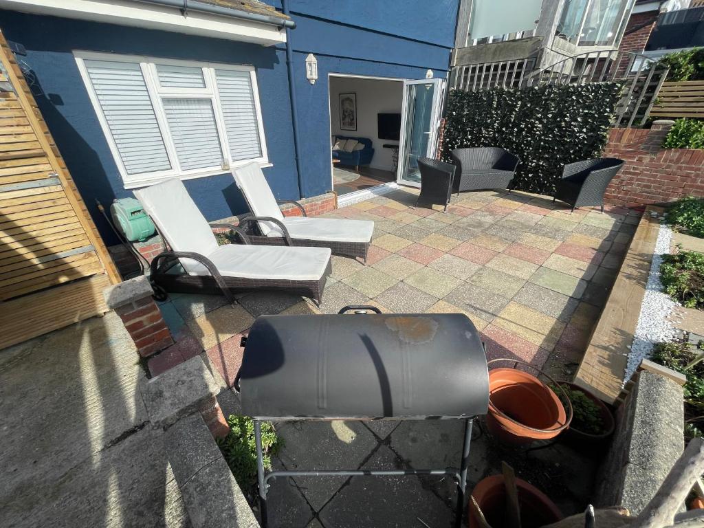 a backyard with a grill and a chair and a house at The Beach House in South Hayling