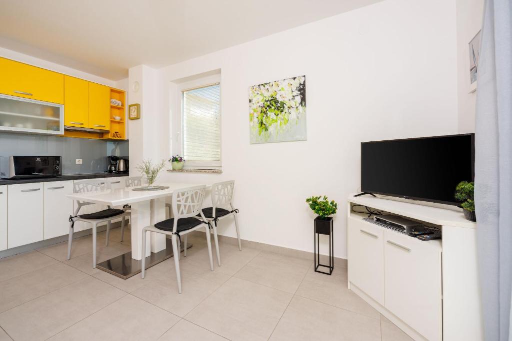 a white kitchen with a table and a tv at Apartments Petak Novi in Dramalj