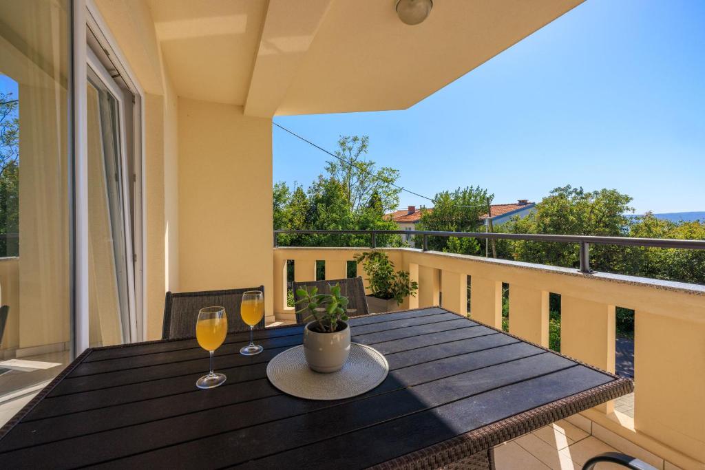 a table on a balcony with two glasses of wine at Apartments Petak Novi in Dramalj