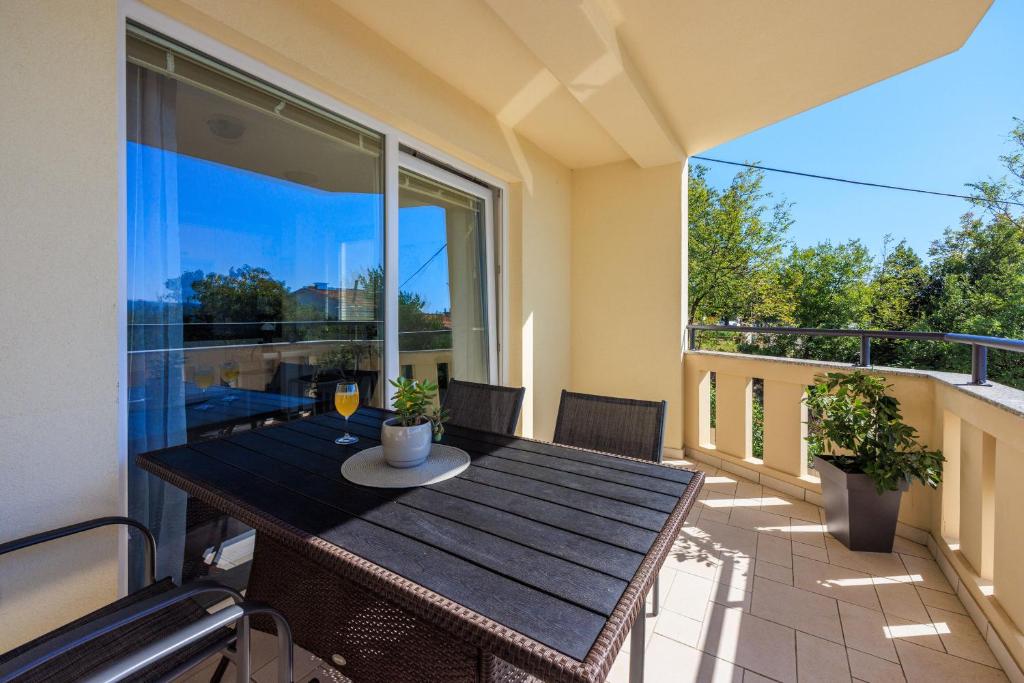 a wooden table on a balcony with a view of the city at Apartments Petak Novi in Dramalj