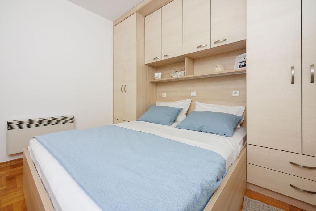 a bedroom with a large bed with blue pillows at Apartments Petak Novi in Dramalj