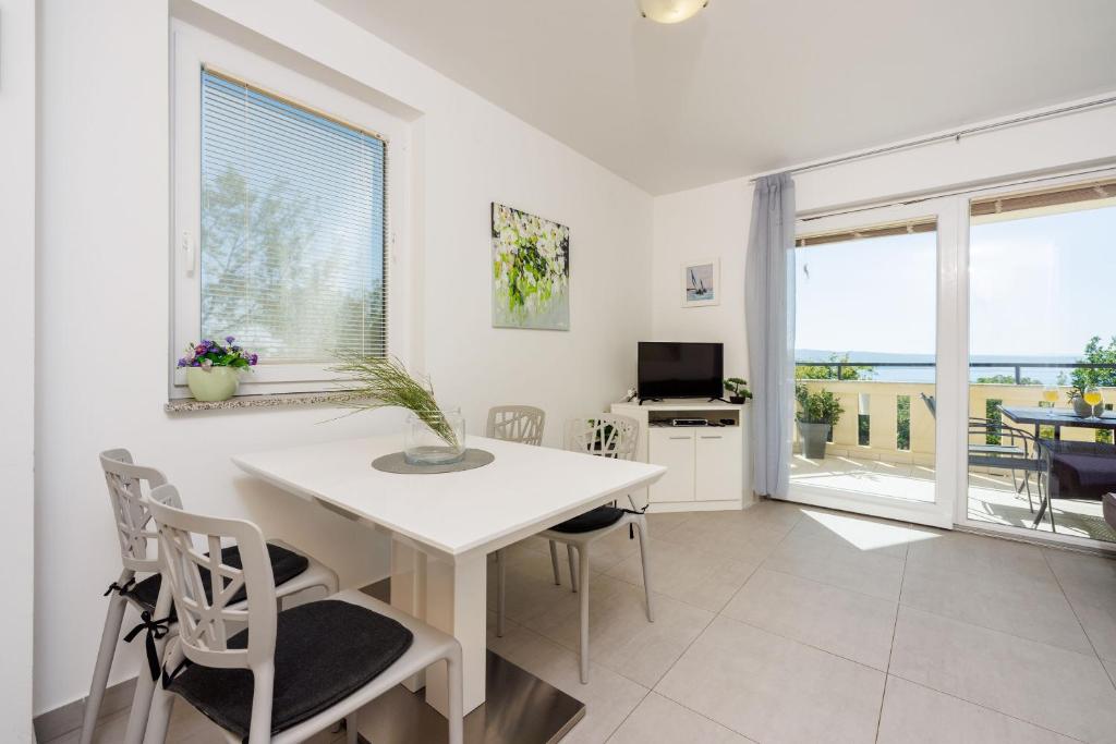 a white dining room with a white table and chairs at Apartments Petak Novi in Dramalj
