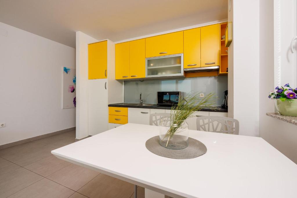 a kitchen with yellow cabinets and a white table at Apartments Petak Novi in Dramalj