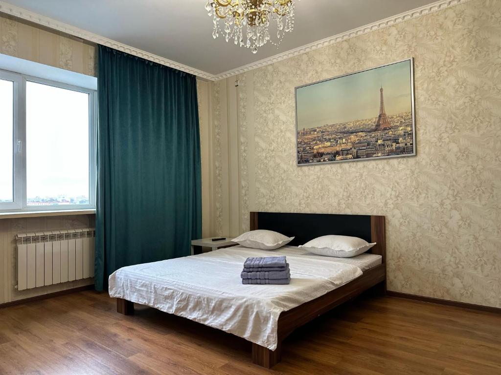 a bedroom with a bed and a chandelier at Элитная квартира возле гипермаркета Дины in Aktobe