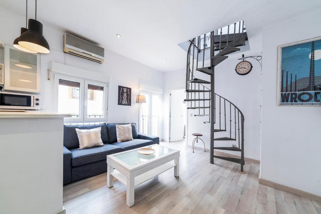 sala de estar con sofá azul y escalera de caracol en Alohamundi Dúplex Alameda II, en Sevilla