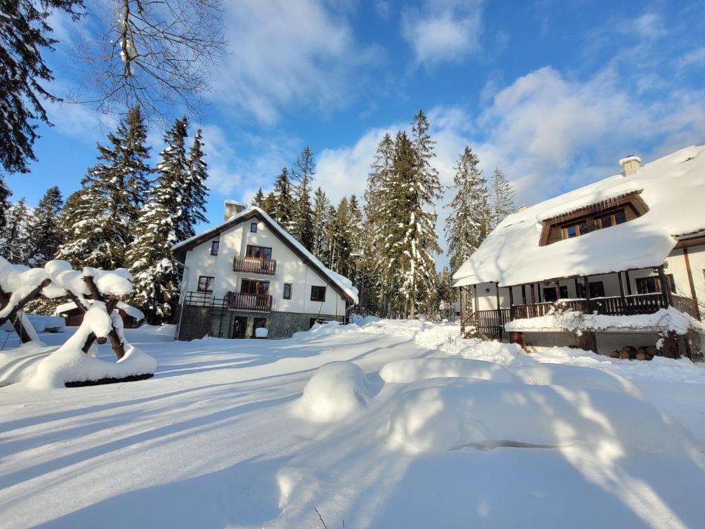 una casa coperta di neve accanto a un edificio di Chaty Tatra a Tatranska Strba