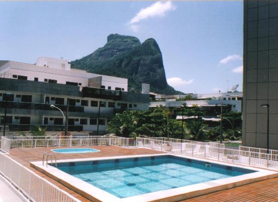 una piscina en un edificio con una montaña en el fondo en Tropical Barra Hotel, en Río de Janeiro