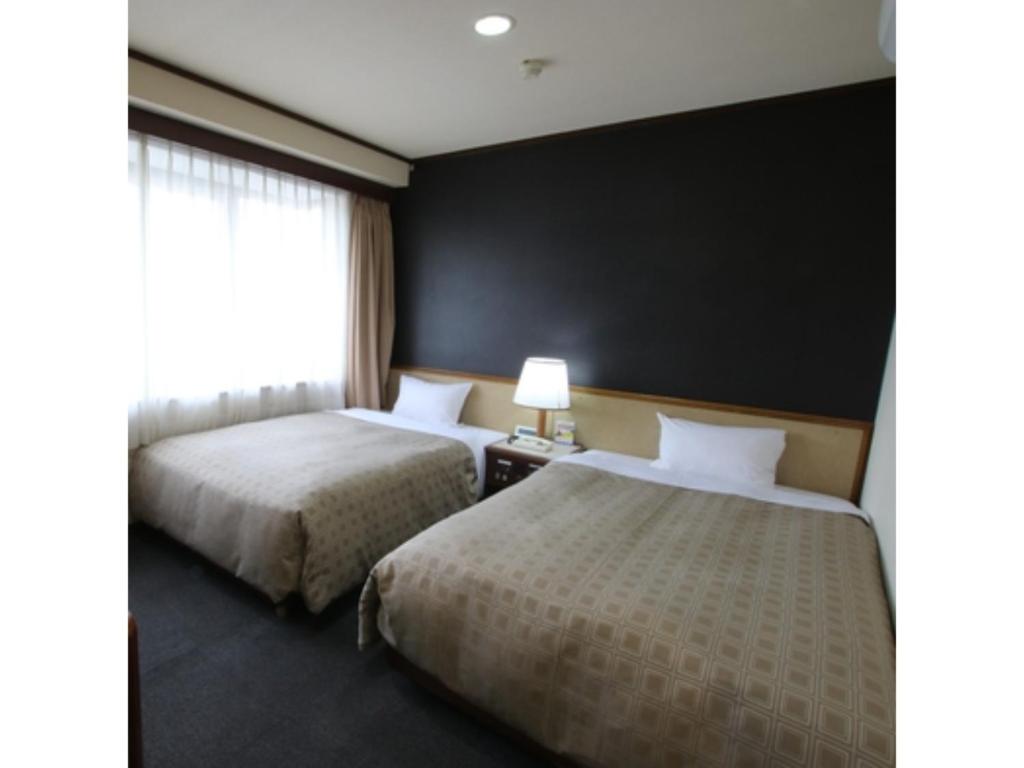 two beds in a hotel room with a black wall at Hotel Aston Hotel Osaka Sakai - Vacation STAY 97585v in Sakai