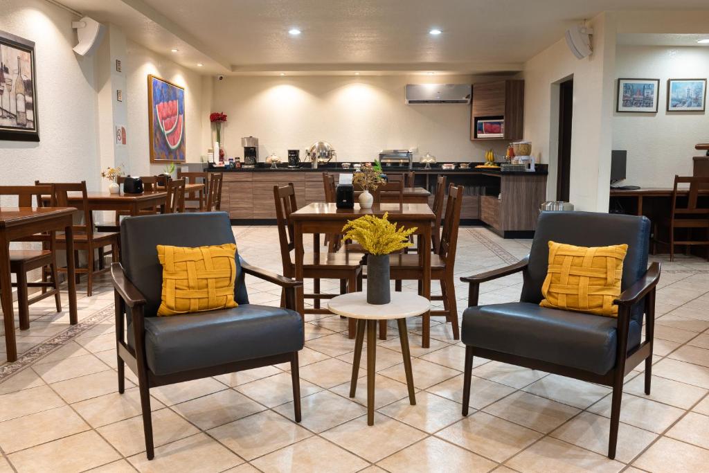 ein Esszimmer mit Stühlen und Tischen sowie eine Küche in der Unterkunft Hotel Quinta San Carlos Inn in Manuel Valdez