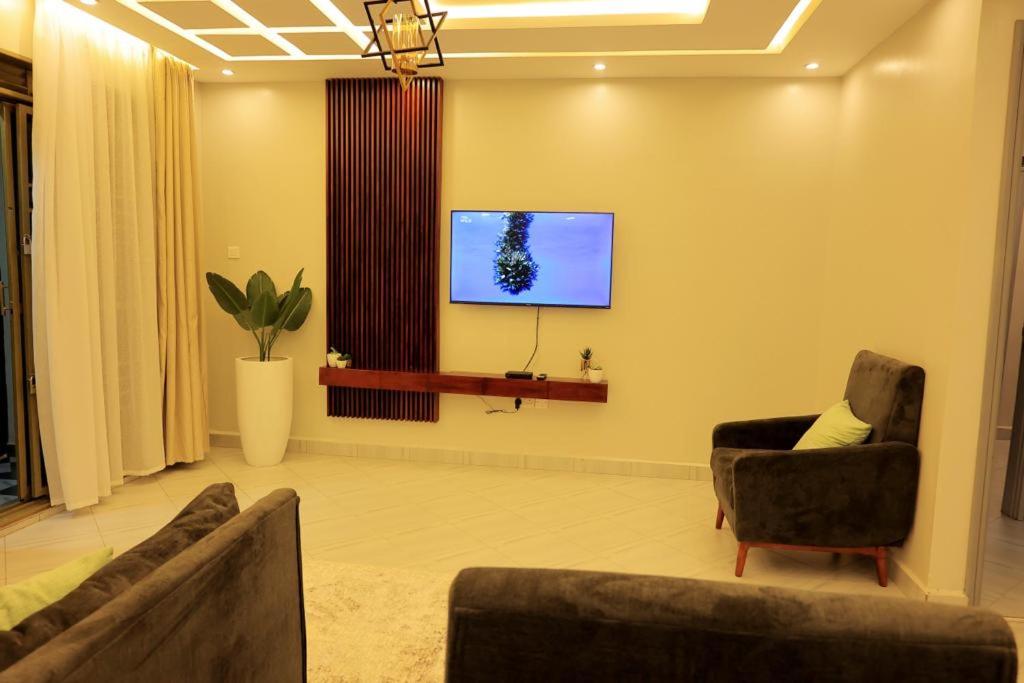 a living room with two chairs and a tv on the wall at The residence Ug in Bulindo
