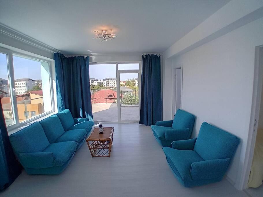 uma sala de estar com cadeiras azuis e uma grande janela em Penthouse cu vedere 270 de grade em Bucareste
