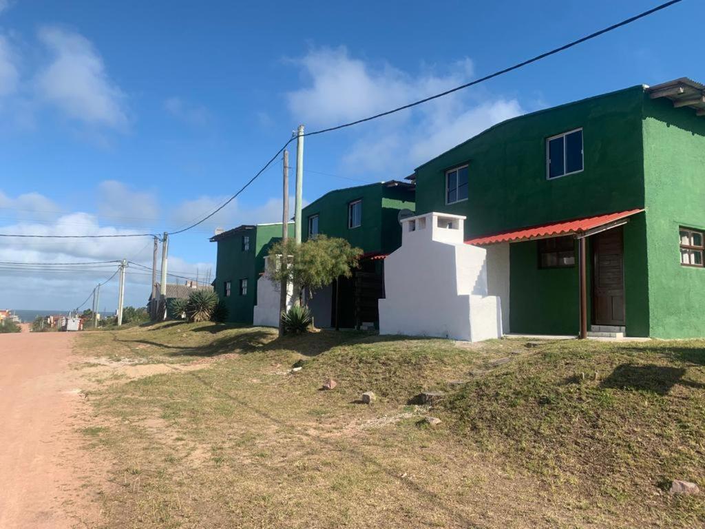 un grupo de edificios verdes y blancos en un camino de tierra en Puerto del sol, en Punta del Diablo