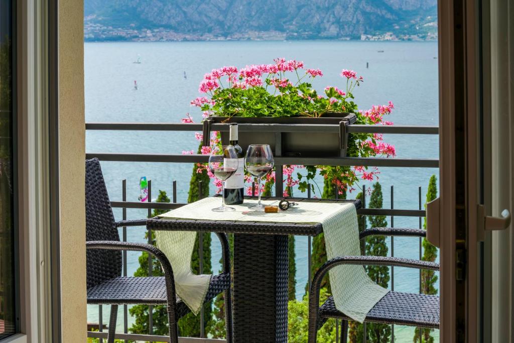 a table and chairs on a balcony with a view of the water at Finestra sul Lago Malcesine Apt Riva in Malcesine