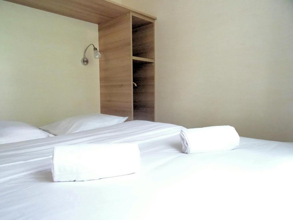 2 camas en un dormitorio con sábanas y almohadas blancas en La Roulotte à 10min de Disneyland Paris - Cabane & Cabanon en Chalifert