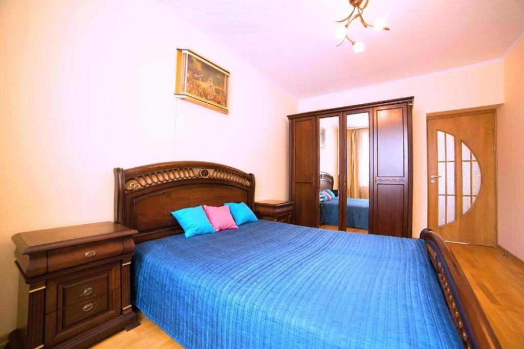 ein Schlafzimmer mit einem blauen Bett und einem Kopfteil aus Holz in der Unterkunft Новобудова 2 кімнати Вернадського 8 in Lwiw