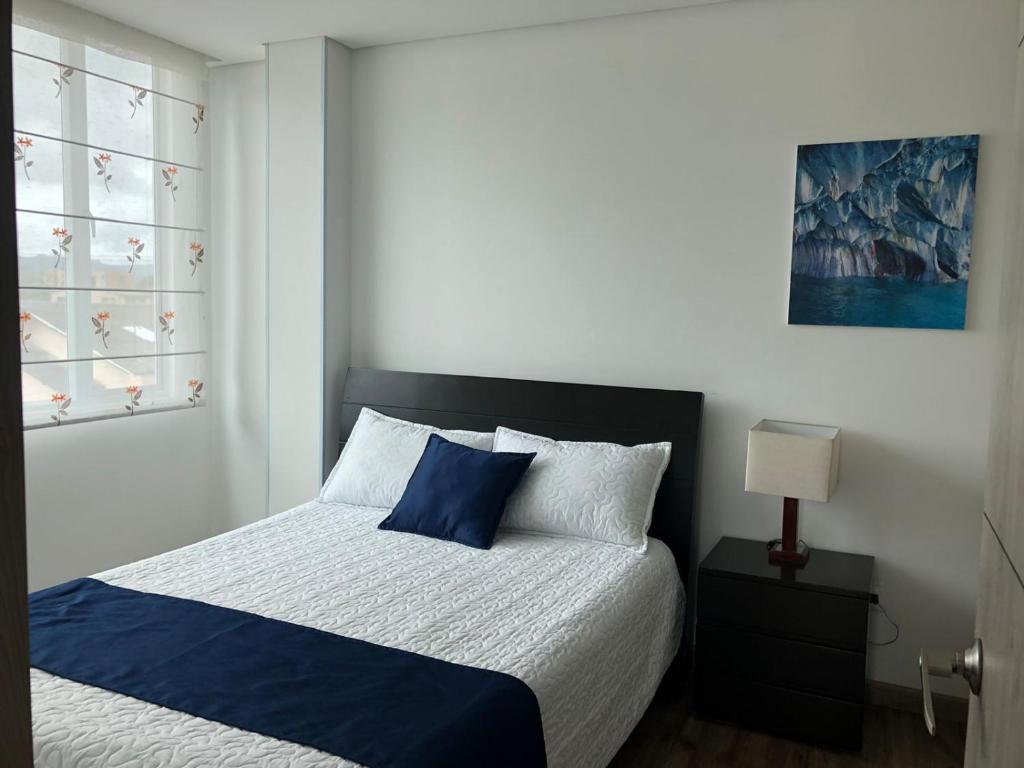 a bedroom with a blue and white bed and a window at Hermoso apartamento con estacionamiento gratuito Chía N1 in Chía
