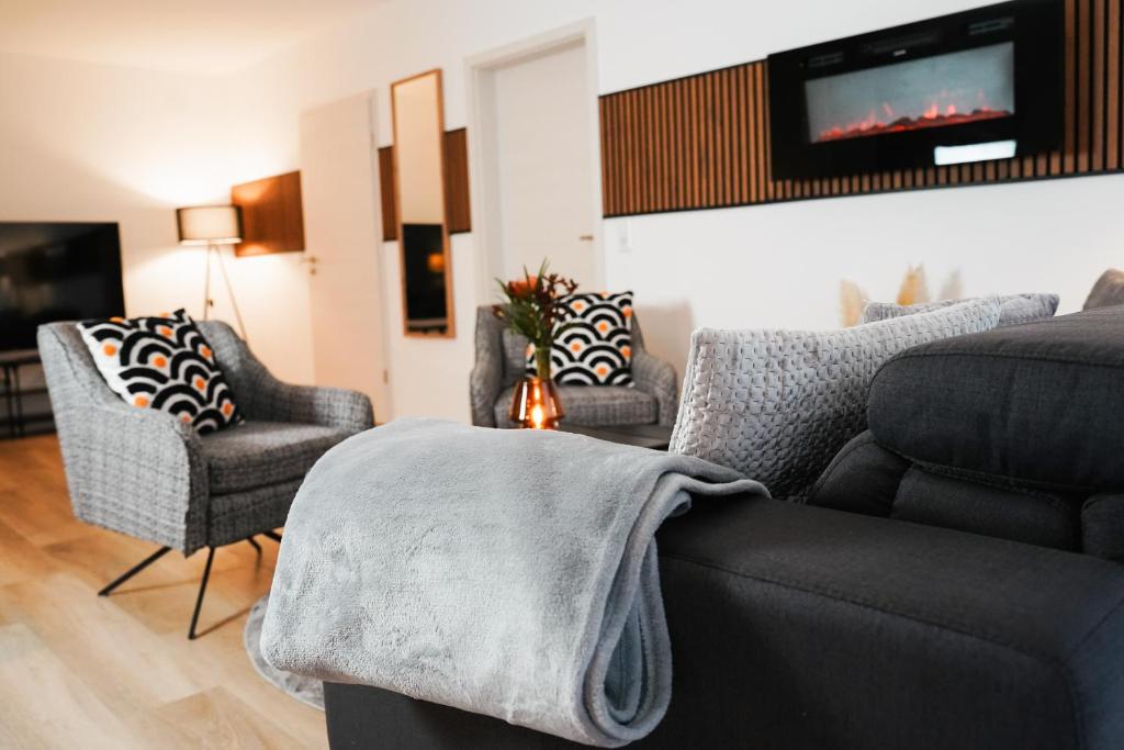 a living room with a couch and chairs and a tv at Paderborn-Oase mit Kamin-Balkon-Stilvolles Zuhause-Self Check-Parkplatz in Paderborn