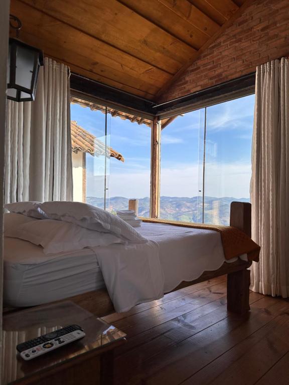 een bed in een kamer met een groot raam bij Nosso Chalet in Lavras Novas
